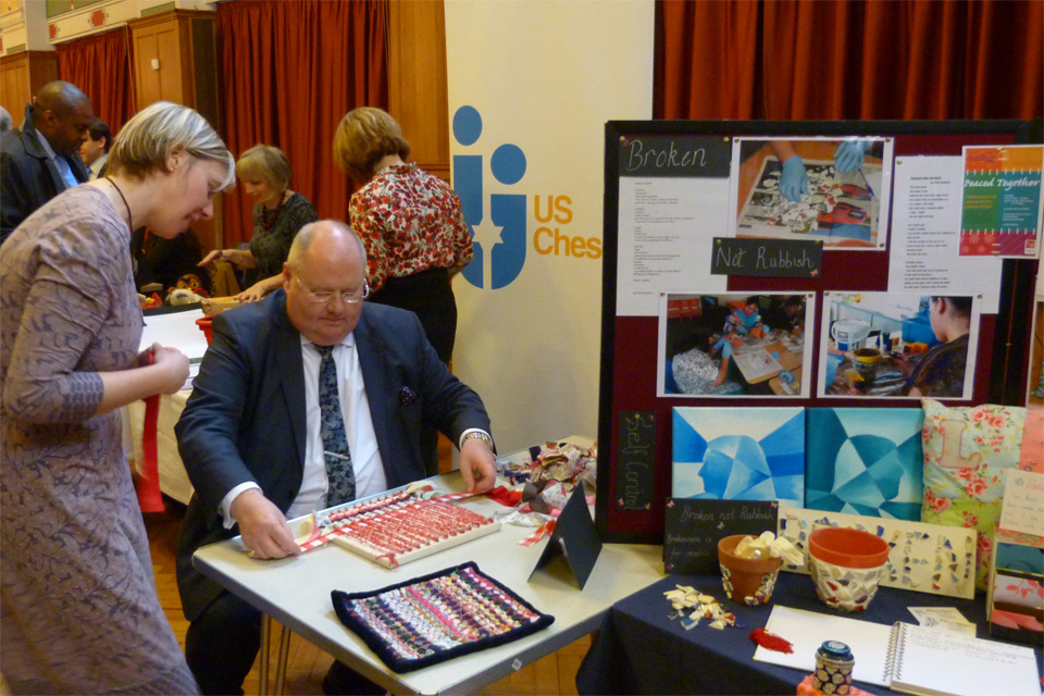 Eric Pickles interacting with the Peaced Together stall, which looks at the process of restoration and hope.