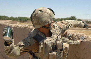 A Royal Marine hurls a smoke grenade, giving protection to a counter-IED team