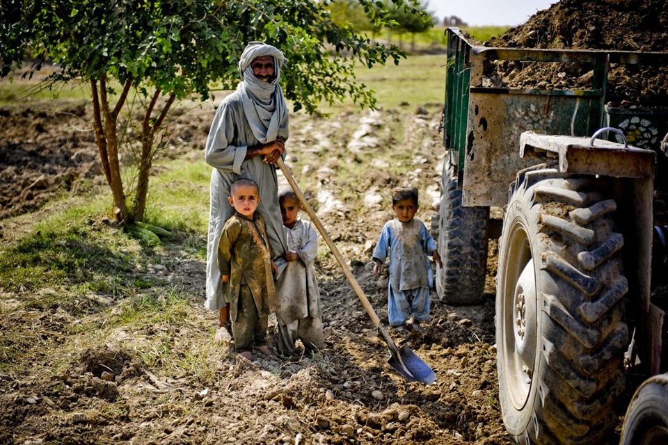 A farmer and his family by a tractor.