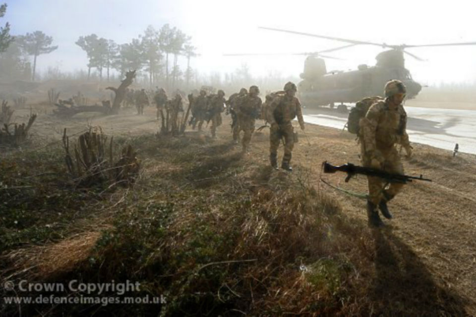 Soldiers in running past a military helicopter.
