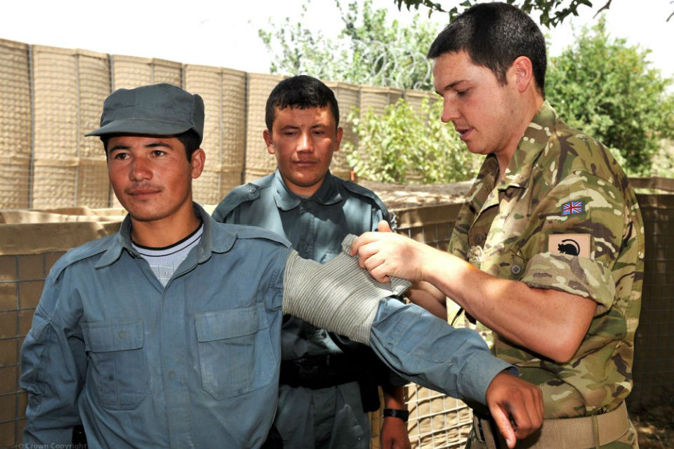 UK soldier showing ANSF soldiers how to bandage an arm.