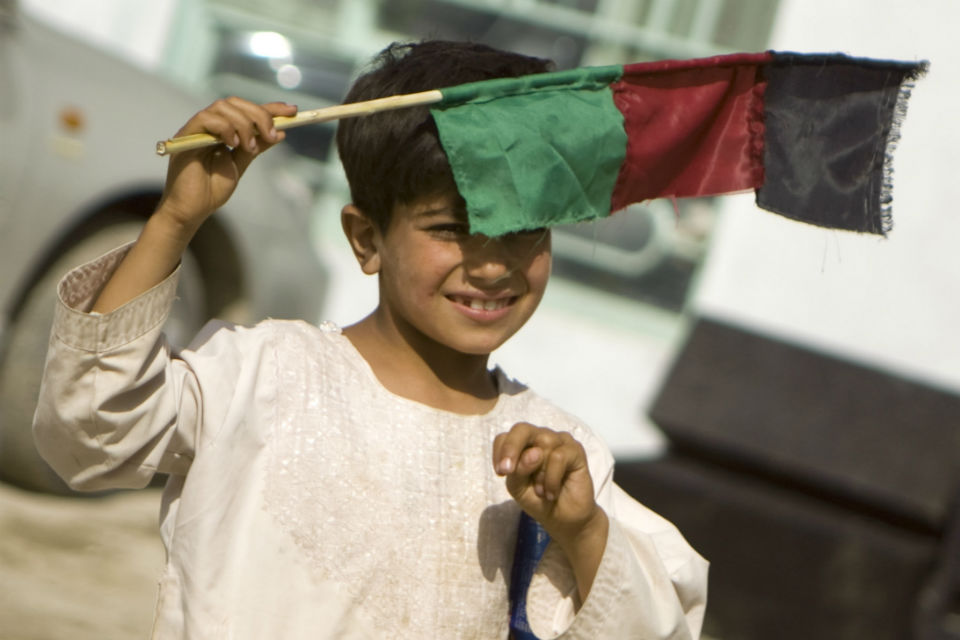 Afghan boy holding a flag.