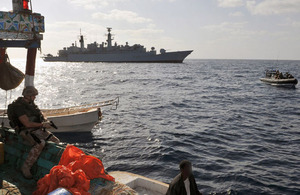 A Royal Marine from HMS Cornwall watches over one of the pirates