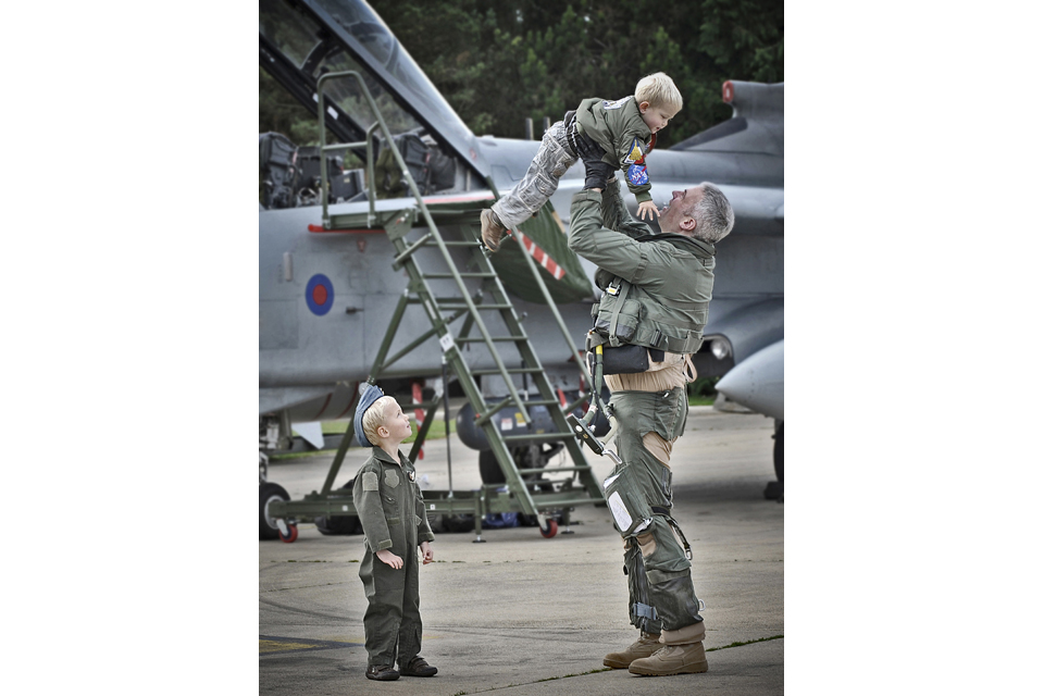 An airman lifts a child