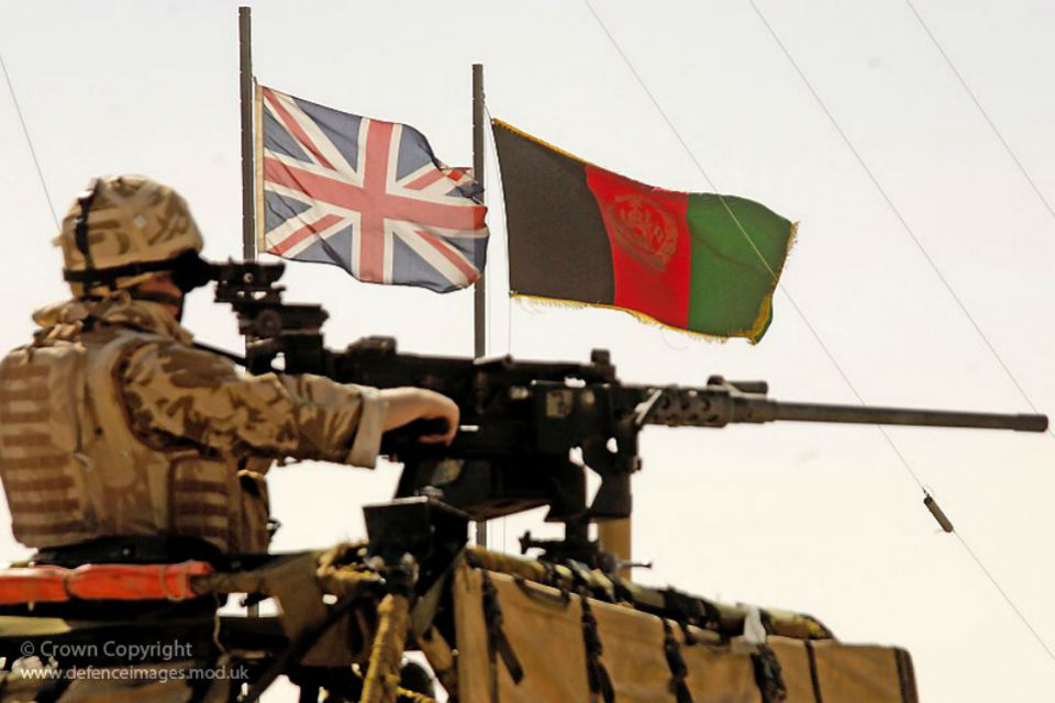 Royal Marine on an armoured vehicle with the Union Jack and Afghan flag.