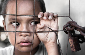 A sad boy behind a fence