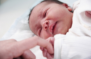 A newborn baby holding a finger