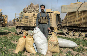 An Afghan policeman poses with bagged substances seized during the operation [Picture: Corporal Ross Fernie, Crown copyright]