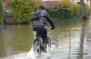 Man cycling through a flood.