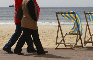 Two people walking along a promenade by a beach