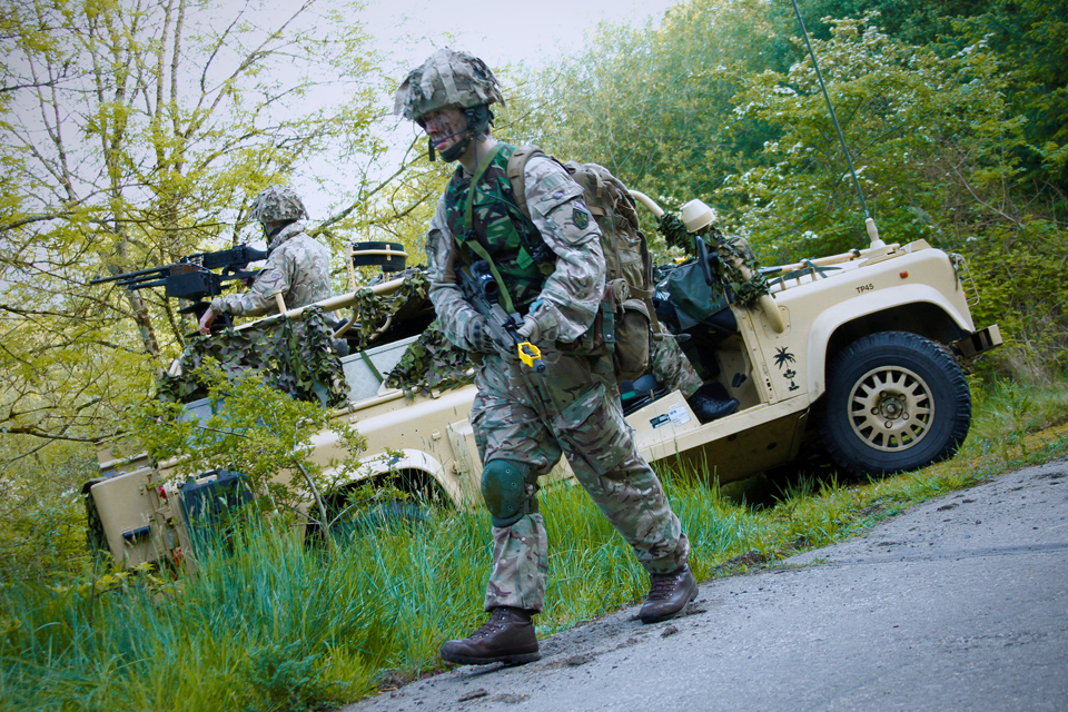 An infantry reservist patrols past a WMIK Land Rover