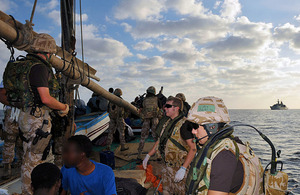 Members of a Royal Marines and Royal Navy boarding party from HMS Cornwall question suspected pirates onboard a dhow, with the Type 22 frigate visible on the horizon (stock image)