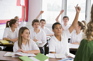pupils with raised hands in classroom