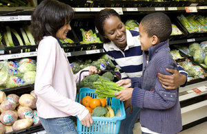 A young boy and a young girl at a supermarket with an adult woman.