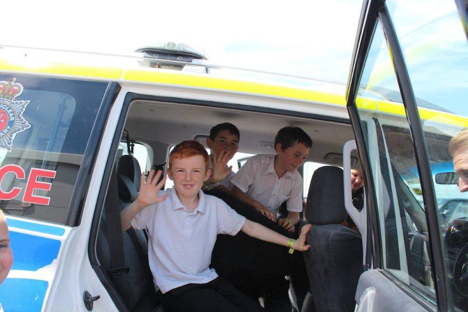 School children sat in police vehicle waving