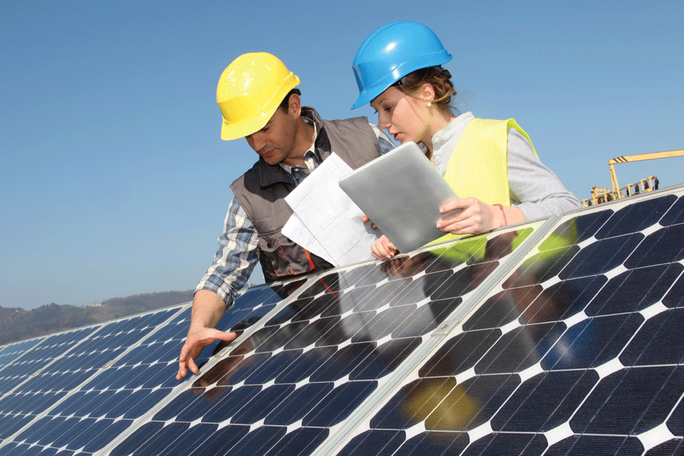 Two officers inspect solar panels installed on a roof.