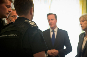 Immigration officers explain their roles to David Cameron and Theresa May.