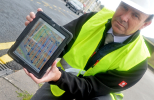 Man with laptop displaying highway data at roadside