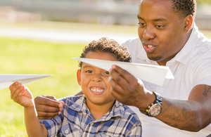 Image of man and child throwing paper aeroplanes.