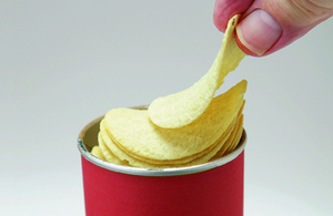 A person taking a crisp from a tube of crisps