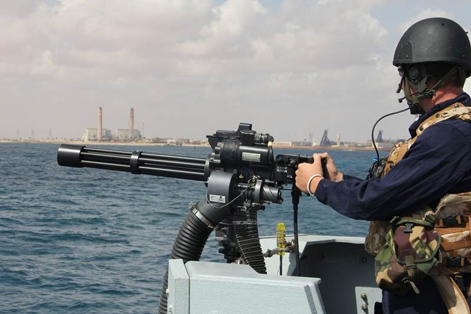 A sailor onboard HMS Bangor mounts the minigun