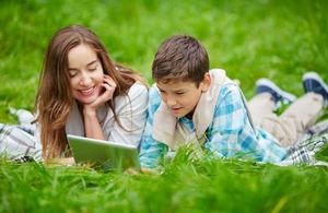 Image of a young woman and a young man looking at a laptop in a park