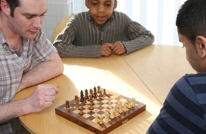 Children playing chess with man