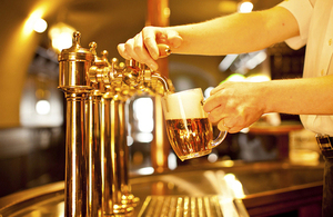 A person pouring a beer from taps at a bar.