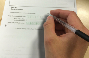 Graphic showing a hand holding a pen and filling an RLE1 form