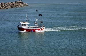 A small red fishing boat returning to harbour