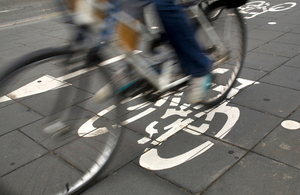 An image of a person cycling on a pavement