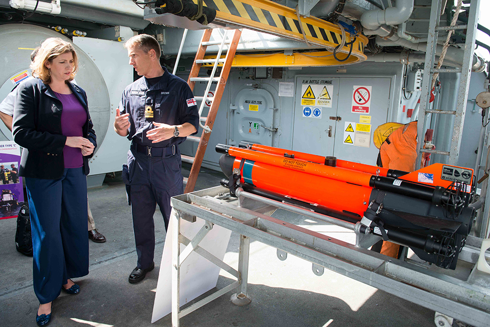 Commanding Officer of HMS Chiddingfold Lieutenant Commander Andy Brown describing SEAFOX, an underwater mine hunting system,  to Armed Forces Minister Penny Mordaunt