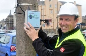 InTouch managing director John Walden holding up a monitoring device against a concrete lamp standard