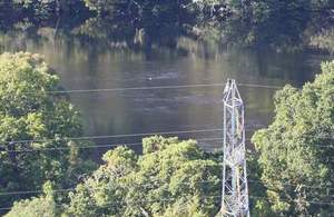 Electricity pylon with sunlit lake in the background
