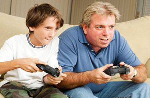 Boy and man playing games consoles.