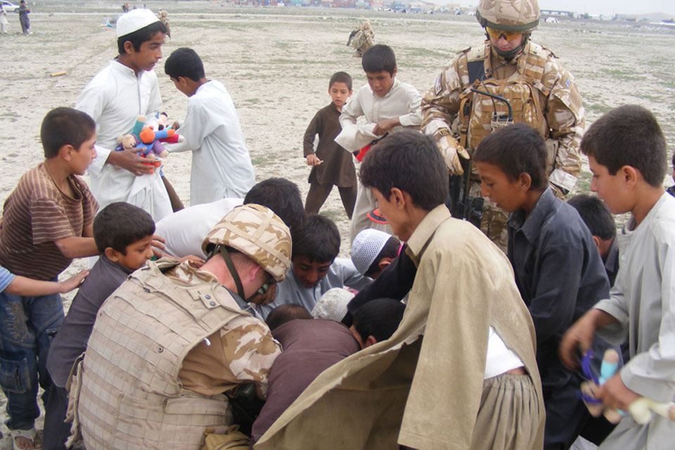 Supplies from an aid drop being distributed to children at Kujah Rawesh School in Kabul by Staff Sergeant John Stephenson of 2 Signal Regiment