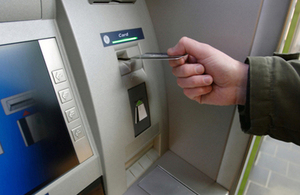 A hand putting a card into a cash point