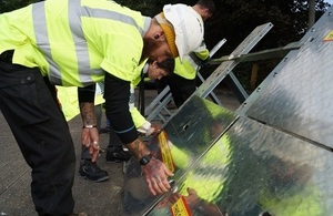 Floods Minister Rory Stewart helps to assemble a temporary barrier