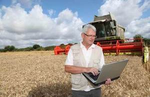 a farmer using a laptop on front of a combine harvester