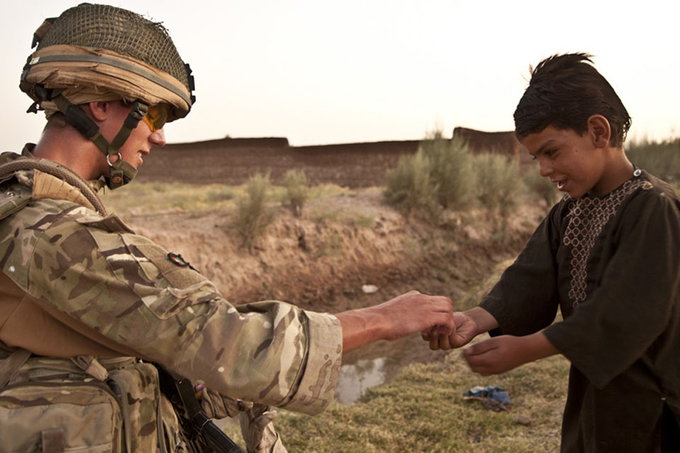 Highlander Mark Mackenzie, 4 SCOTS, gives an Afghan child a treat during a patrol in Lashkar Gah District, Helmand province