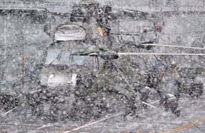 Crew members secure a Sea King helicopter during a whiteout on board HMS Illustrious