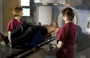 2 radiotherapists monitoring a cone beam imaging scan of a patient.