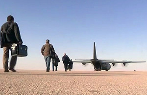 Oilfield workers make their way to an RAF C-130 Hercules