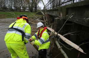 2 Environment Agency staff under a bridge clearing debris from a watercourse