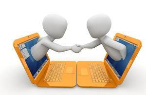 two animated people reaching out of laptops to shake hands