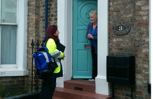 An Environment Agency flood support officer talking to a resident at her front door.