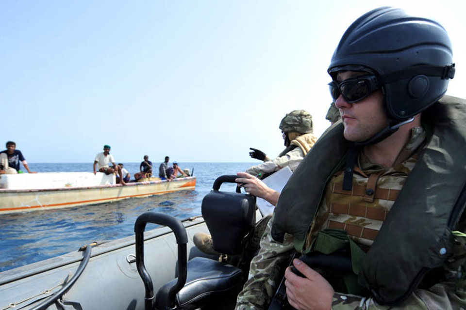 A sailor keeps watch as the Boarding Officer gathers vital information from local fishermen