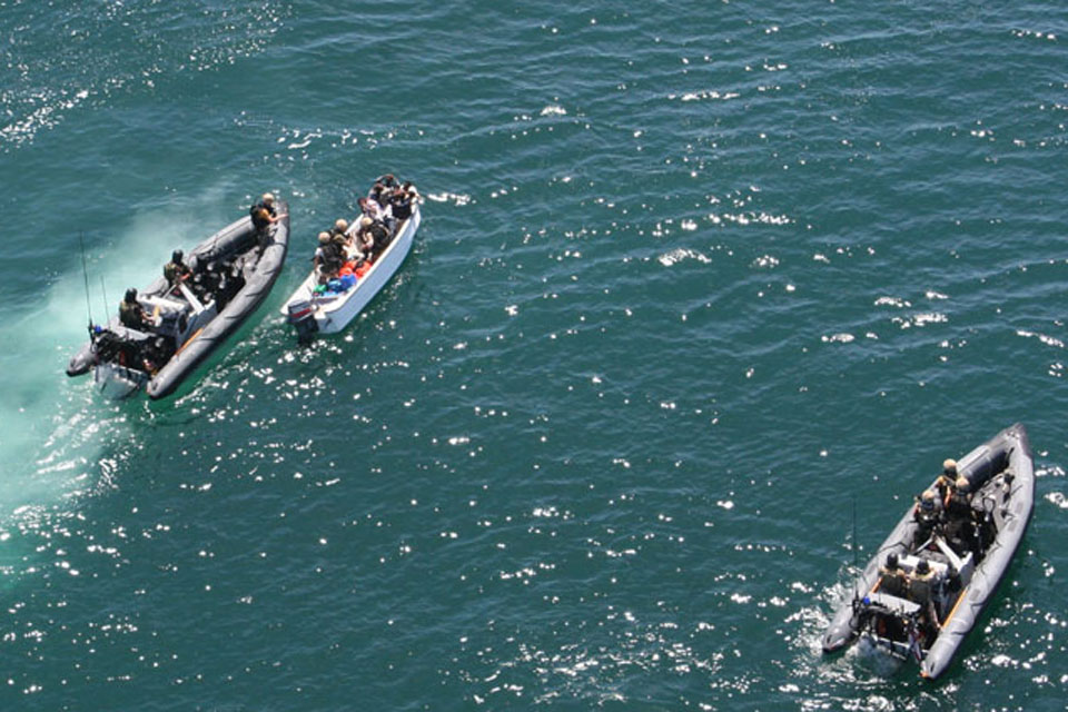 Royal Marines and Royal Navy sailors from HMS Montrose investigate a boat with suspected pirates onboard