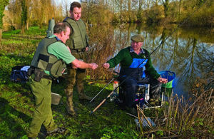 An angler having his rod licence checked by an enforcement team