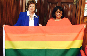 Baroness Anelay and Baroness Verma hold up the rainbow flag.